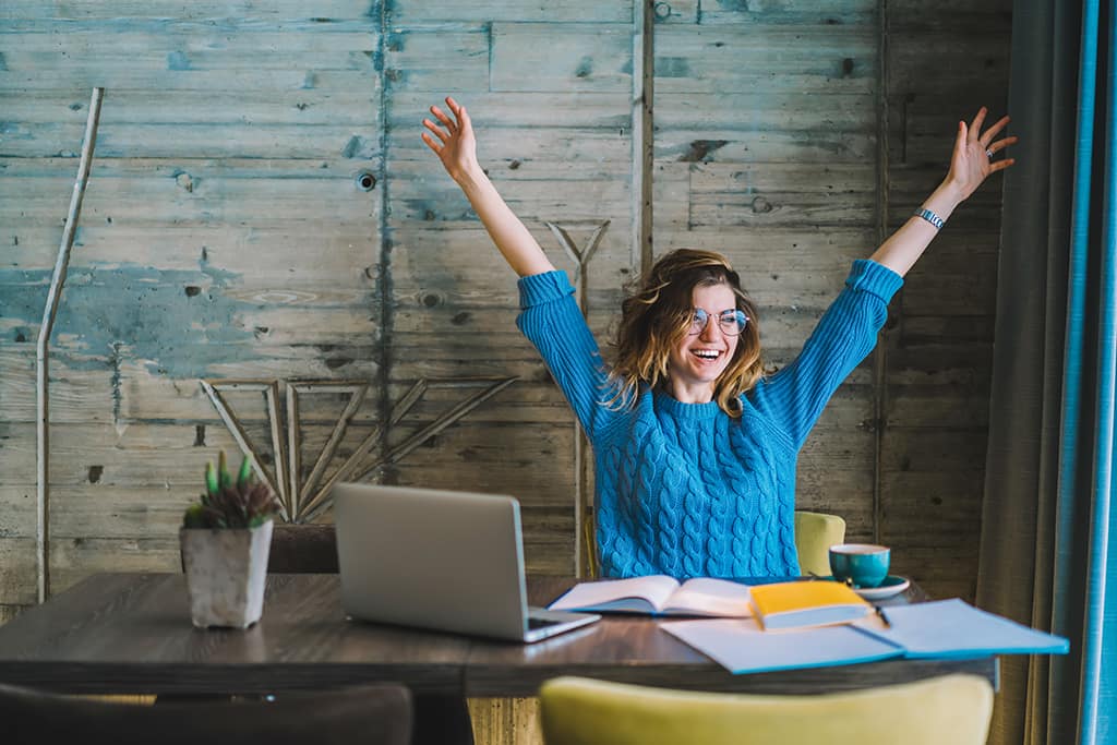 Woman at desk with hands in the air